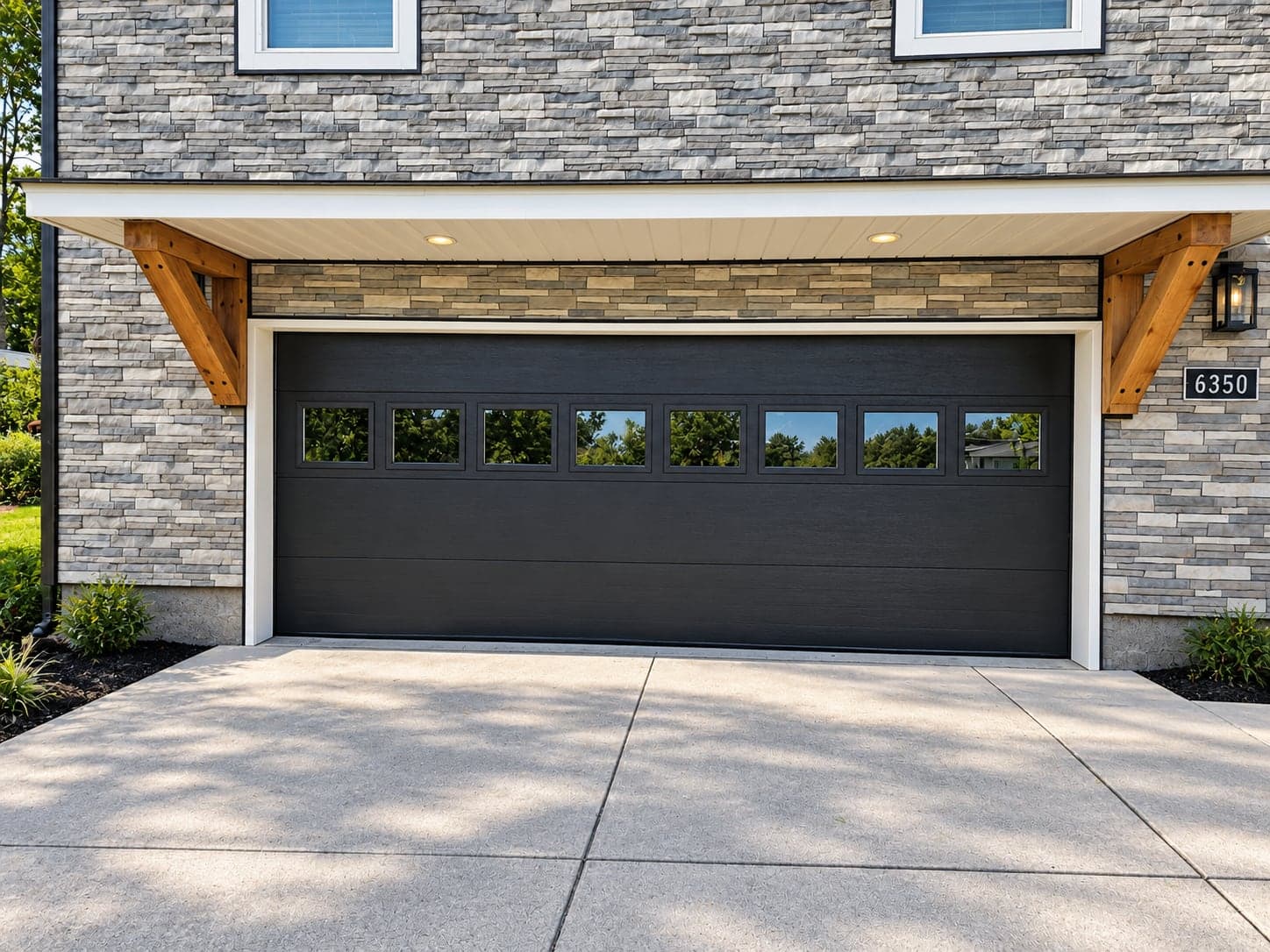 A black windowed garage door under a stone portico