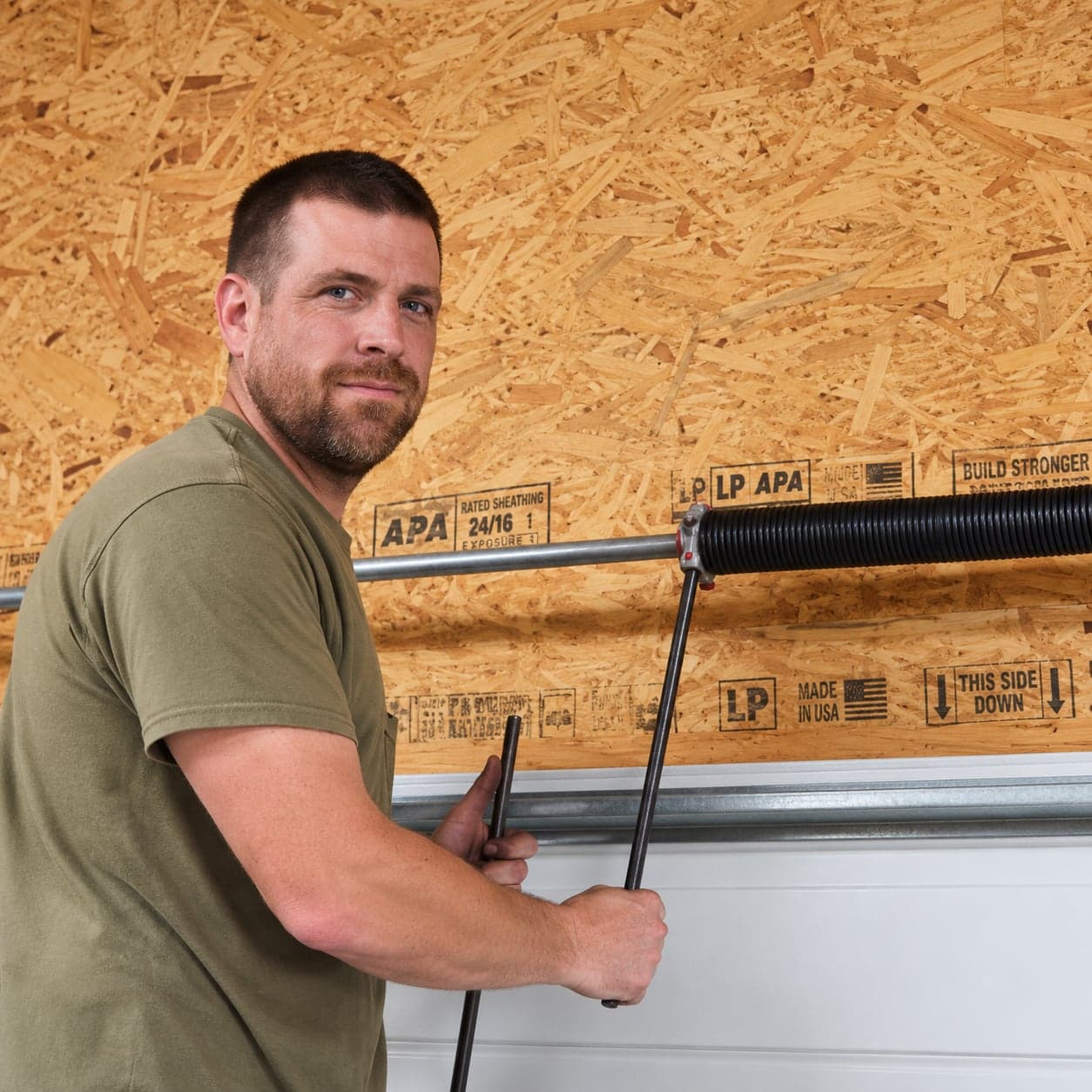 Justin Vaughn, owner of Vaughn Overhead Door, winding a torsion spring above a garage door