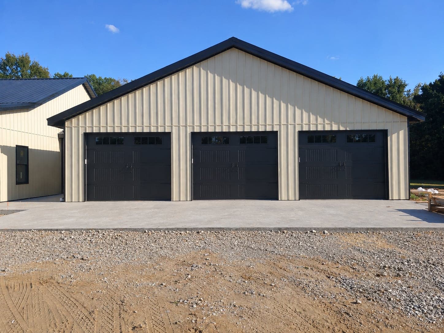 Three black overhead doors on a new tan steel building