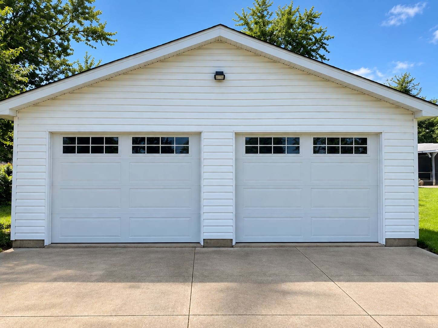A white detached two-car garage with two white doors